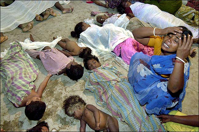A woman greiving over the bodies of children on the ground.