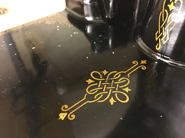A closeup of a decal on the machine bed, an ornate Celtic knot in gold on a black background.