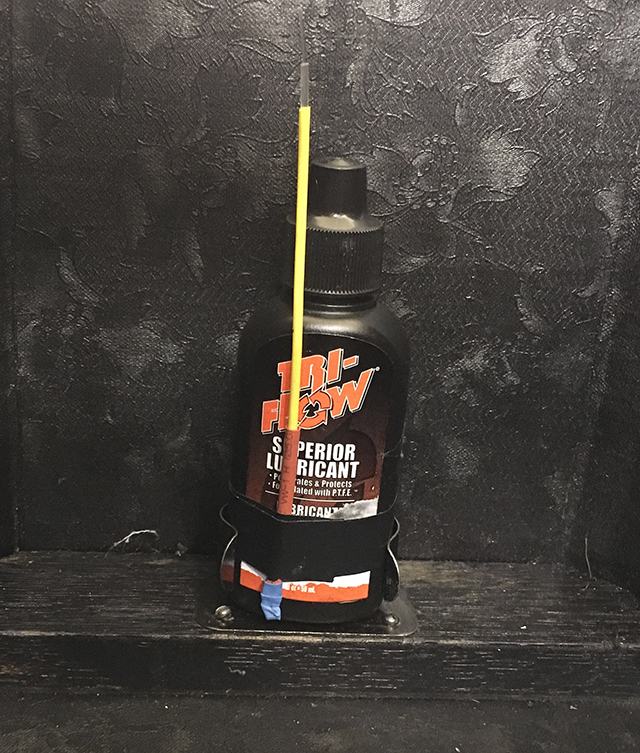 A bottle of Tri-Flow lubricant is held inside the oil can clip at the bottom of the carrying case. A straw is fastened to its side with electrical tape.