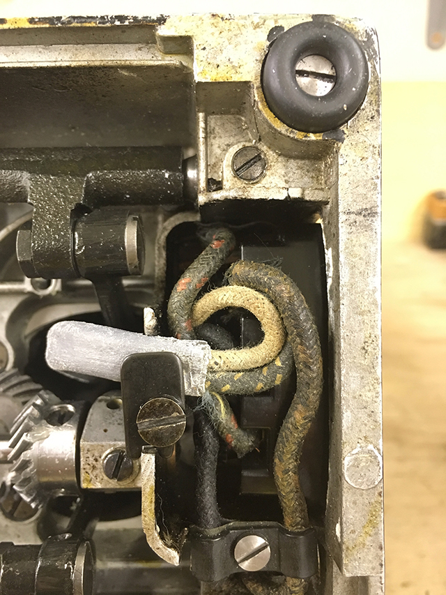 A closeup of the original machine wiring, showing the lead cladding over the light and the original cloth wires.