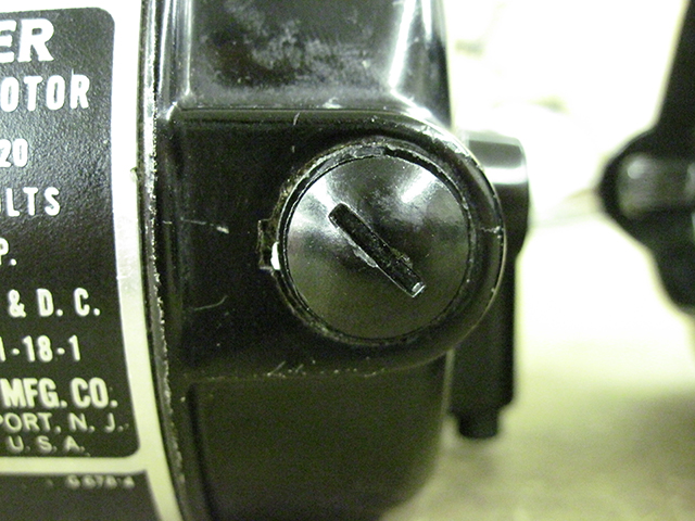 A closeup of a motor brush cap on the Singer motor.